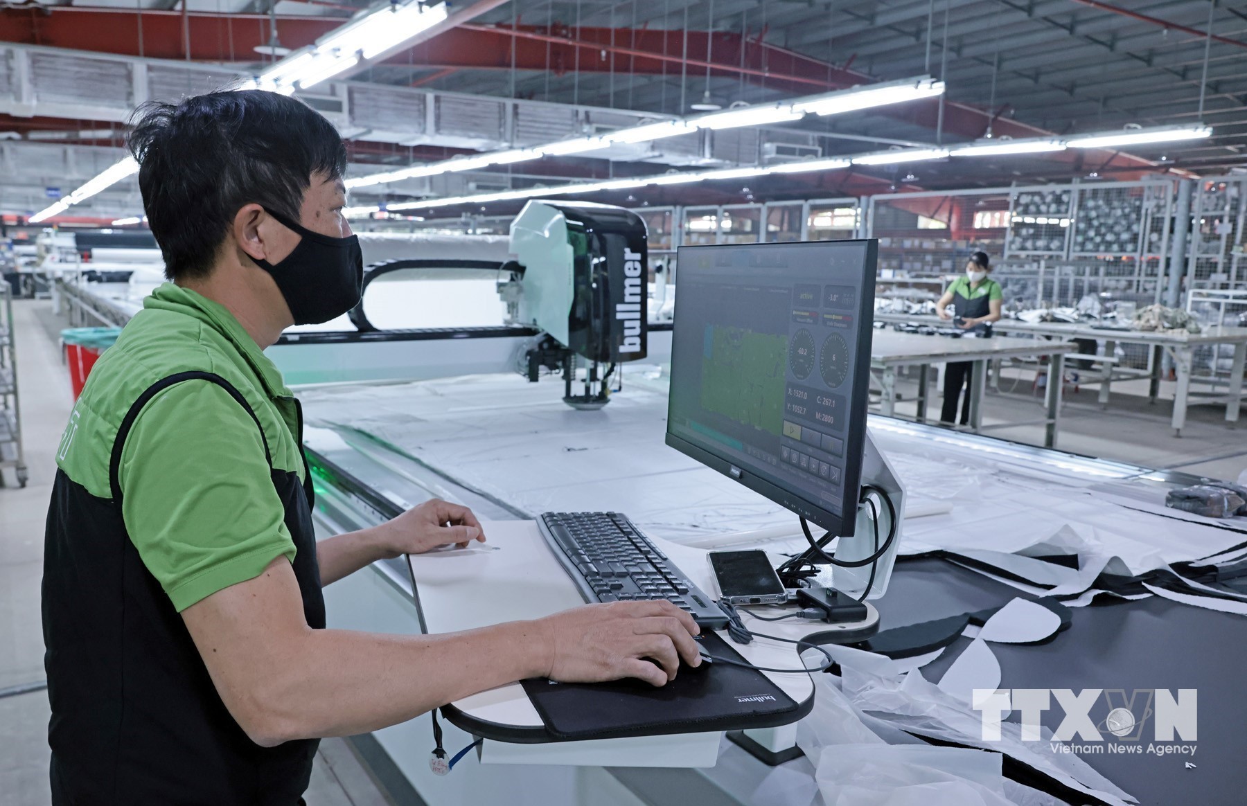 Công nhân dùng máy tính để điều khiển máy cắt tự động tại Công ty Maxport Thái Bình. (Ảnh: Trần Việt/TTXVN)